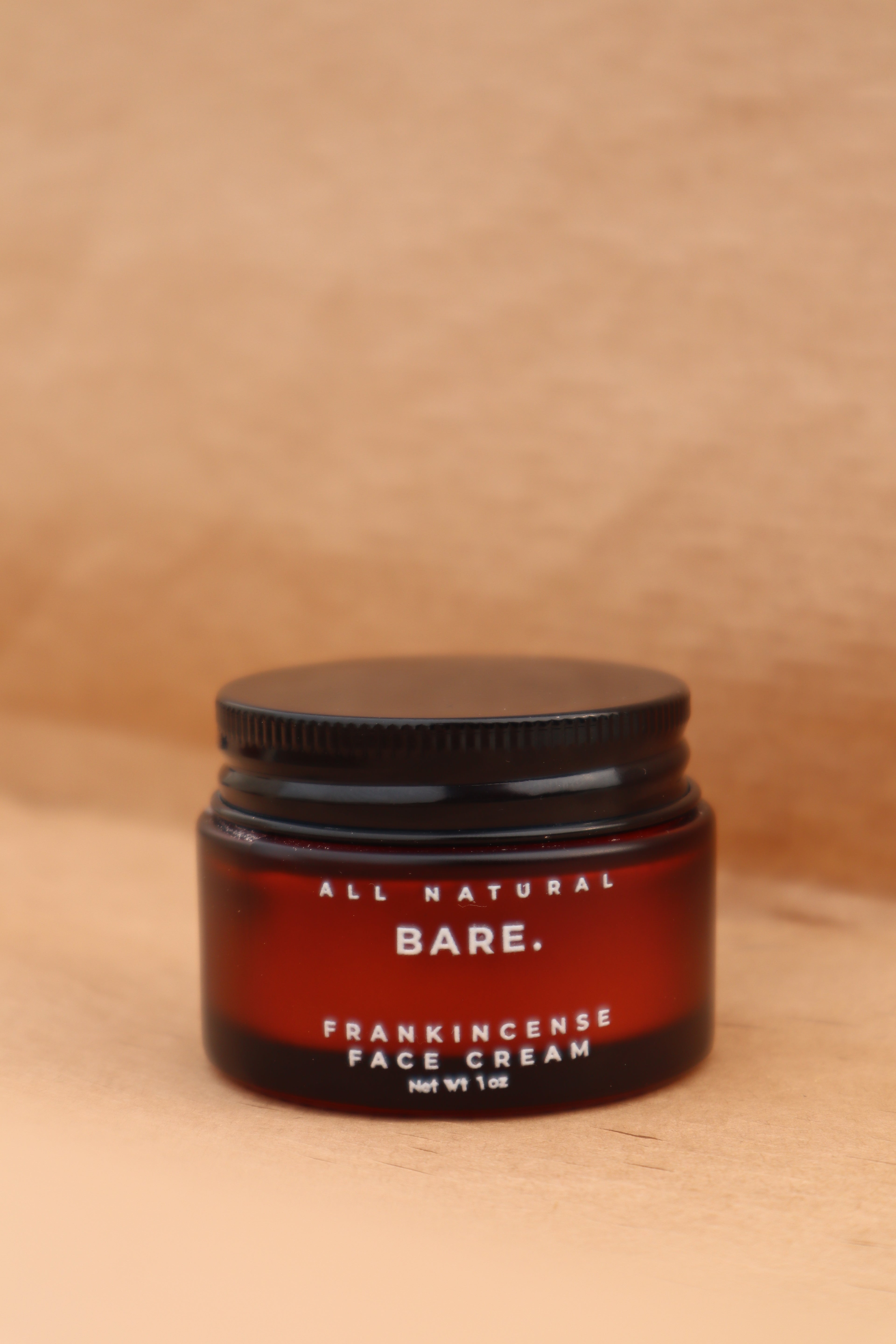 Jar of Bare All Natural Frankincense Face Creme on a wooden surface