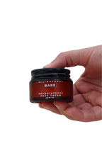 Hand holding a frosted amber glass jar of Bare Naturals Frankincense Face Cream on a clean white background, rich tallow face moisturizer for dry, normal and sensitive skin, non-comedogenic anti-aging skincare.