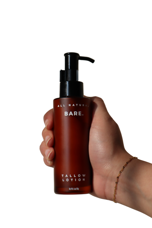 Hand holding a 106 ml frosted amber glass pump bottle of Bare Naturals Tallow Lotion against a clean white background, lightweight daily lotion that supports the natural skin barrier, gives long-lasting hydration, absorbs quickly with no residue, and is gentle for dry, normal and sensitive skin.
